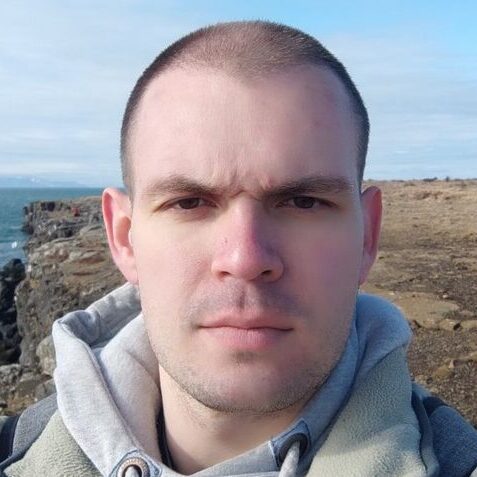 Artsiom baranouski the growth manager wearing a hoodie standing atop a rocky place while staring at the camera